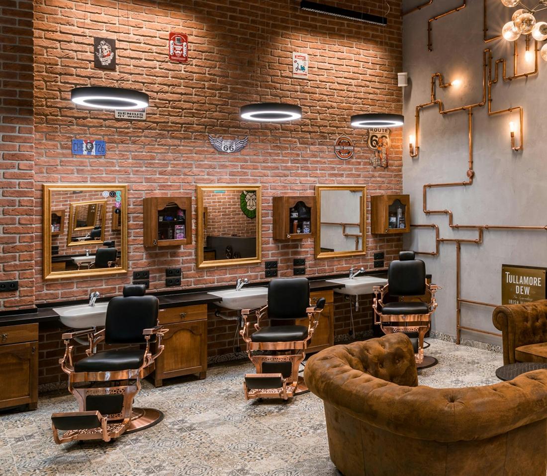 Barbershop interior with leather barber chairs, gold-framed mirrors and an exposed brick wall