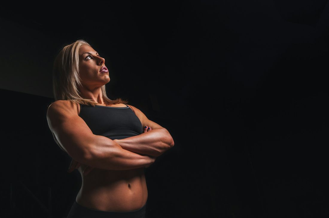 Portrait of Ilse Botha, head of strength, arms crossed, lit from the side against a dark background