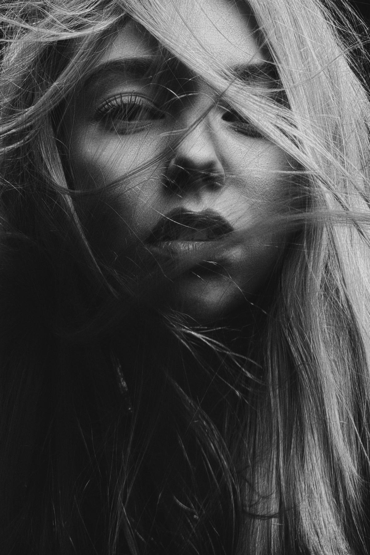 Black and white portrait with hair blown across a woman's face