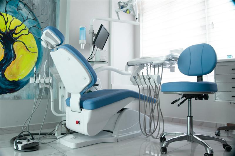 A blue dental chair beside a large abstract painting